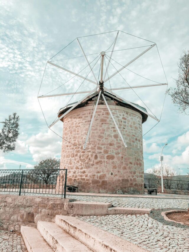 Historic stone windmill surrounded by cobblestone in Alaçatı, Turkey.